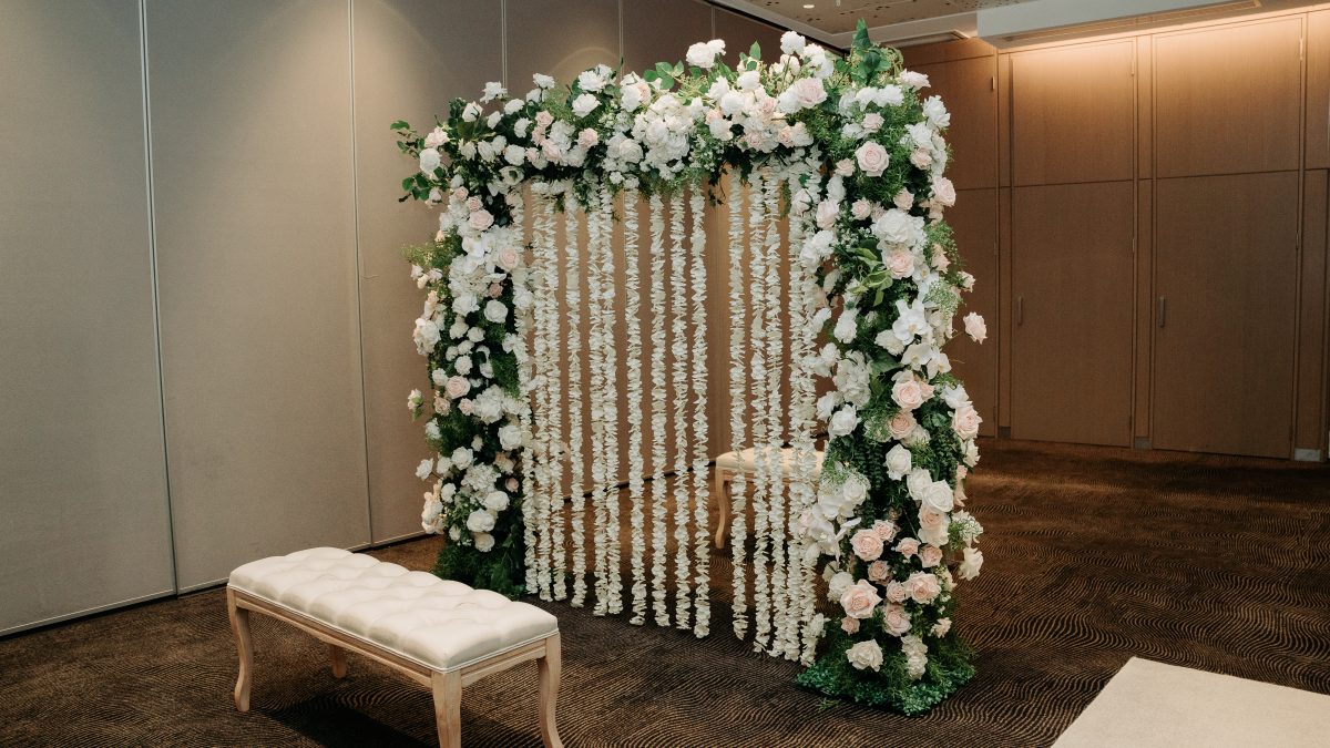 Indian styled wedding ceremony with artificial floral partition and two benches on either side.