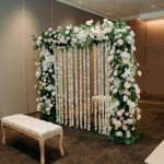 Indian styled wedding ceremony with artificial floral partition and two benches on either side.