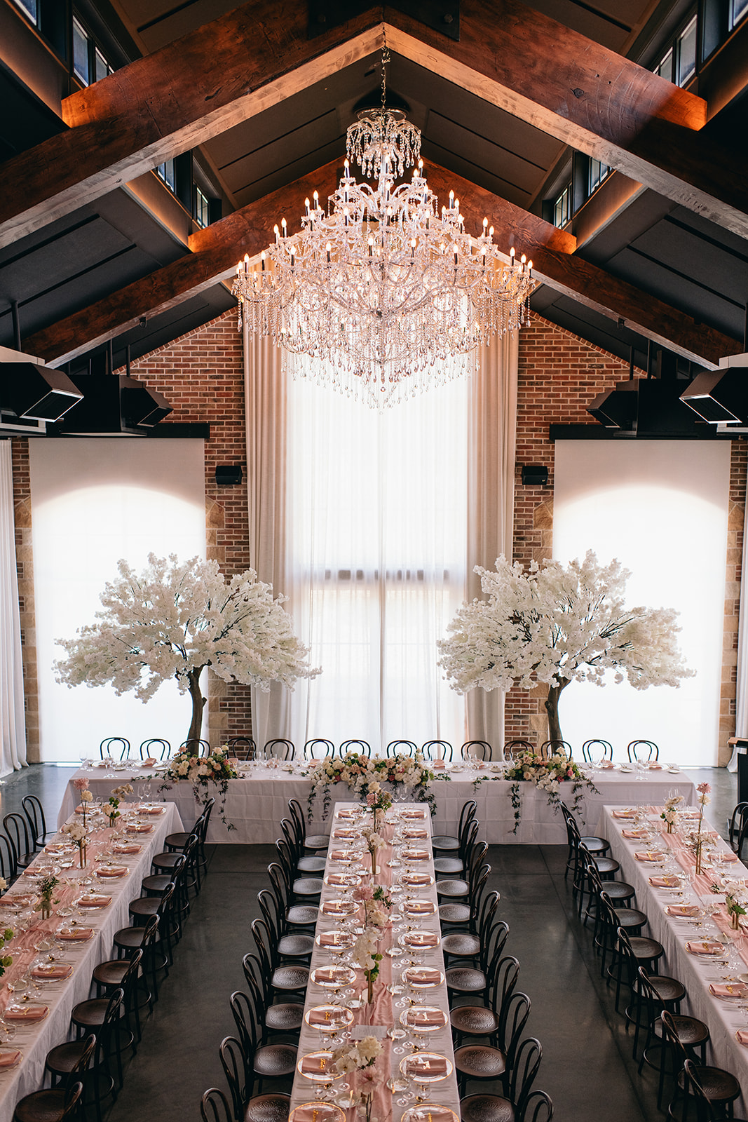 Balcony view of the bridal table framed with cherry blossom trees and styled by luxury wedding planner and designer The Hourglass House.
